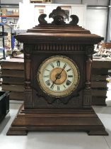 An Edwardian oak cased Ansonia mantel clock, the architectural case with stepped pediment and carved