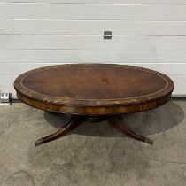 An oval low table, with a polished gilt tooled-leather surface, on four splayed supports W: 117 cm
