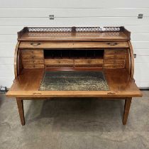 An Empire style cylinder bureau, fret carved gallery, fitted interior and slide out desk, above