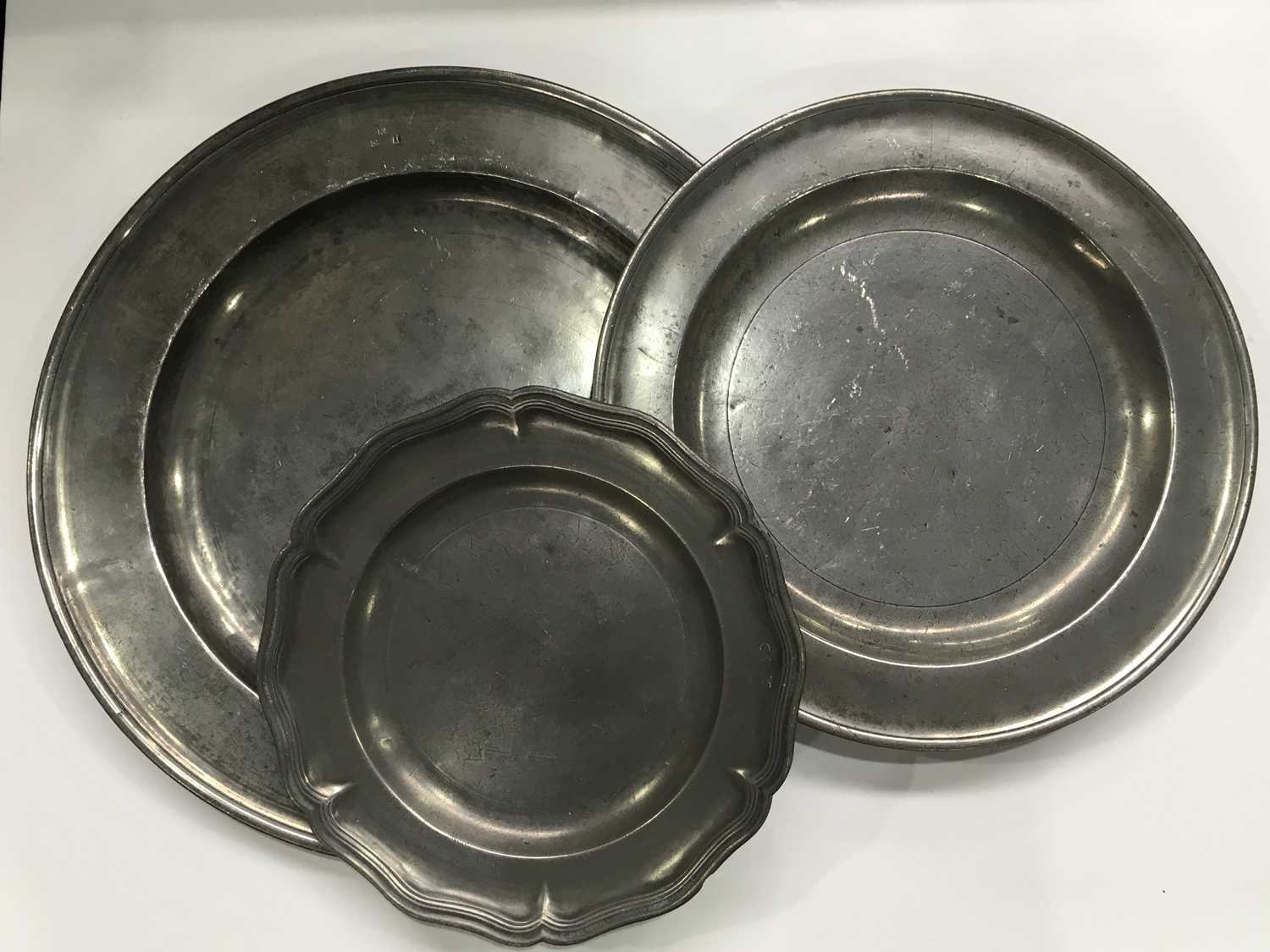 Two antique pewter chargers and a serpentine-rimmed plate, with touchmarks, largest 46cm diameter (