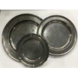 Two antique pewter chargers and a serpentine-rimmed plate, with touchmarks, largest 46cm diameter (