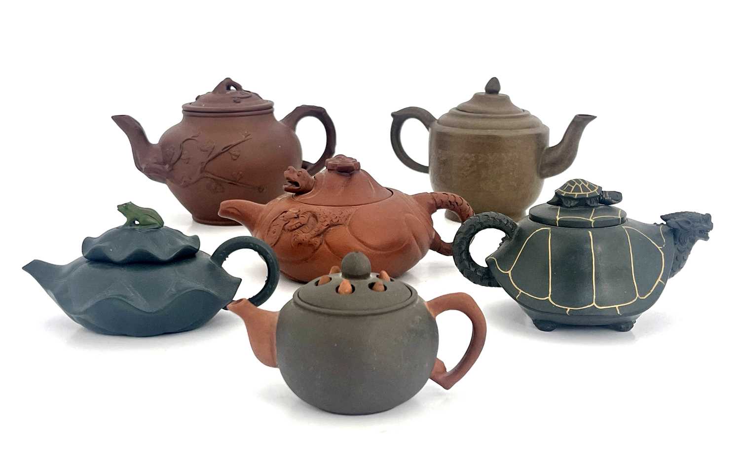 Six Oriental earthenware teapots, relief moulded figural and zoomorphic designs in terracotta and