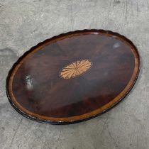 A wavy edge wooden tray, oval form, quarter veneered and with marquetry inlaid paterae to the centre