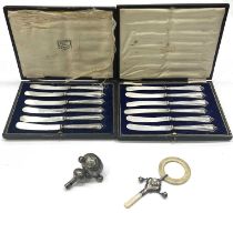 Two cased sets of six silver-handled fruit knives and two baby's rattles (4)