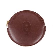 Cartier, a circular Bordeaux coin purse, crafted from smooth burgundy leather, featuring the maker's