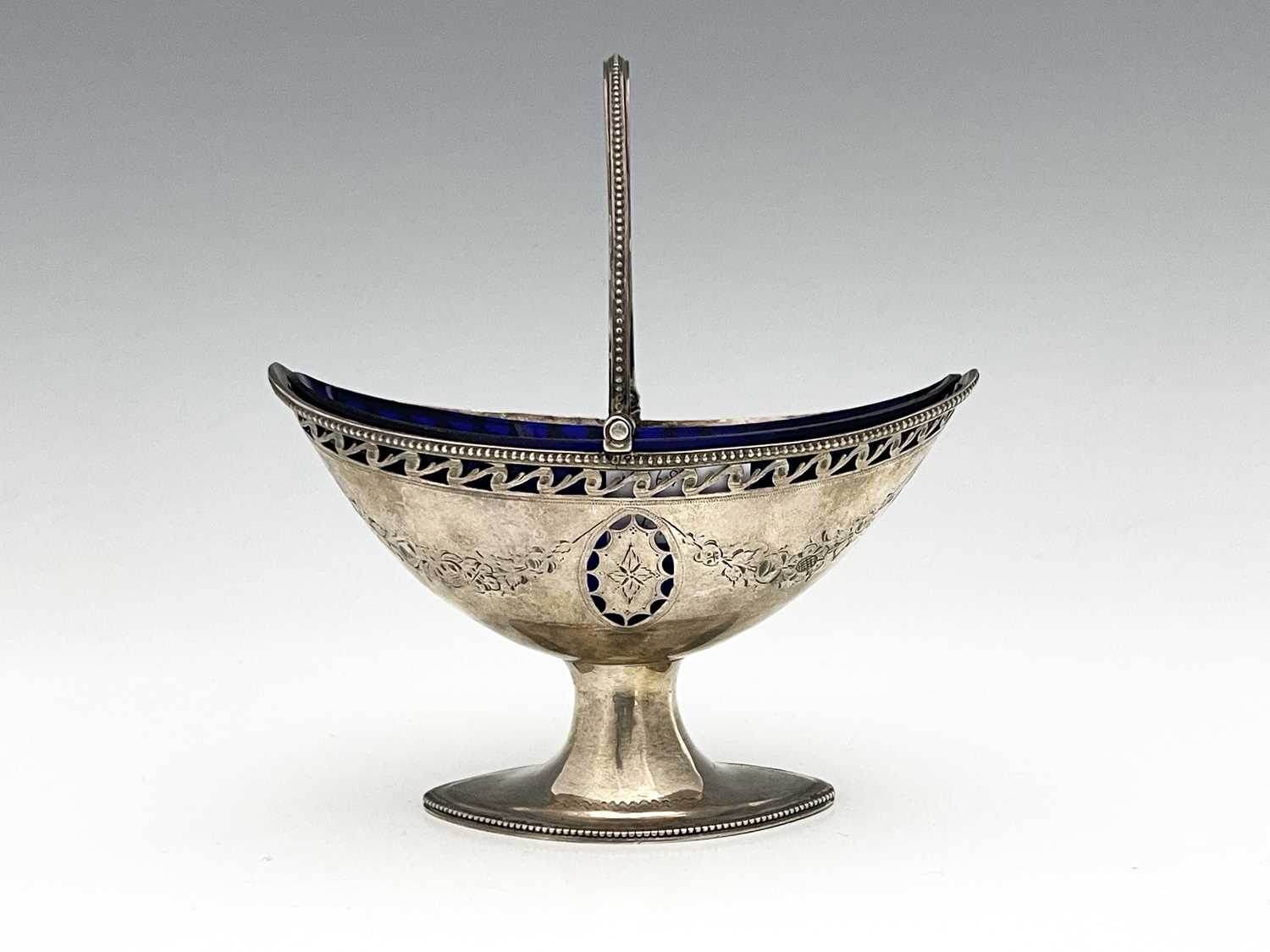 A George III neoclassical silver swing handle basket, of navette form, the body with bead edge