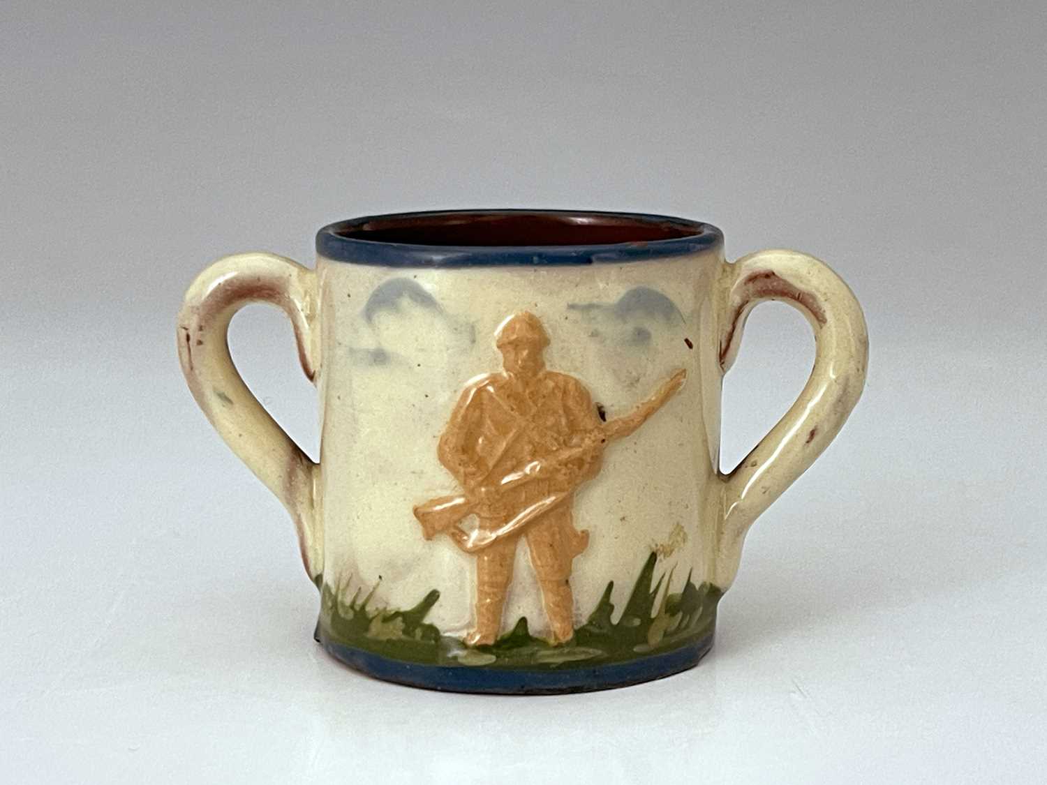Aller Vale, Military Interest, an Art Pottery miniature twin handled tig, 1900, relief moulded