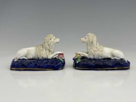 A pair of Staffordshire porcelain dog figure groups, modelled as resting poodles with dead ducks, on