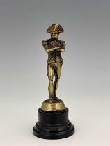 A cast brass figure of Napoleon, modelled standing, on turned ebonised base, 16cm high