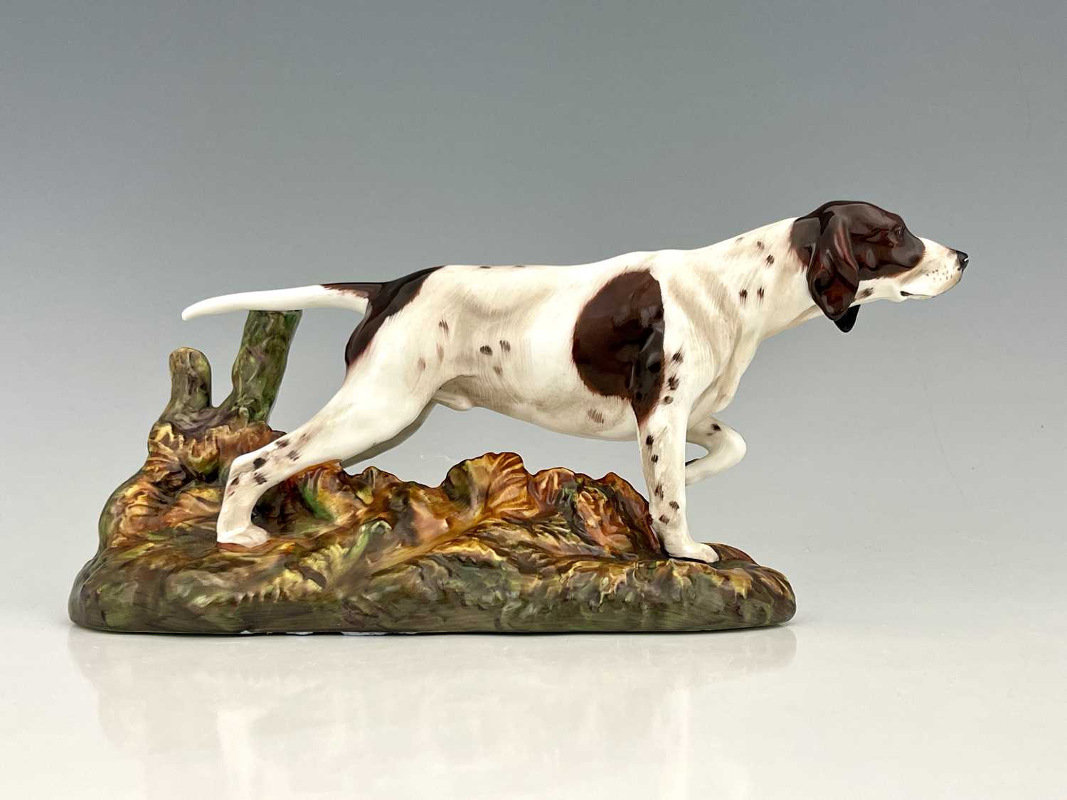 A Doulton figure of a Pointer dog, HN 2624, modelled alert in thicket with a tree stump, 30cm long