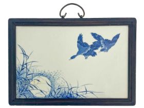 A Japanese blue and white painted plaque, decorated with ducks flying over a wetland scene, framed