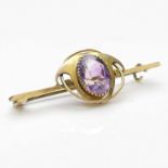 Murrle Bennett, an Arts and Crafts gold and amethyst bar brooch, the central oval facet cut stone
