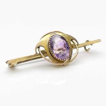 Murrle Bennett, an Arts and Crafts gold and amethyst bar brooch, the central oval facet cut stone