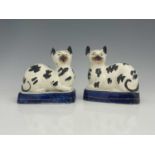A pair of Staffordshire pottery cats, mid 19th century, modelled seated, on blue bases, black sponge