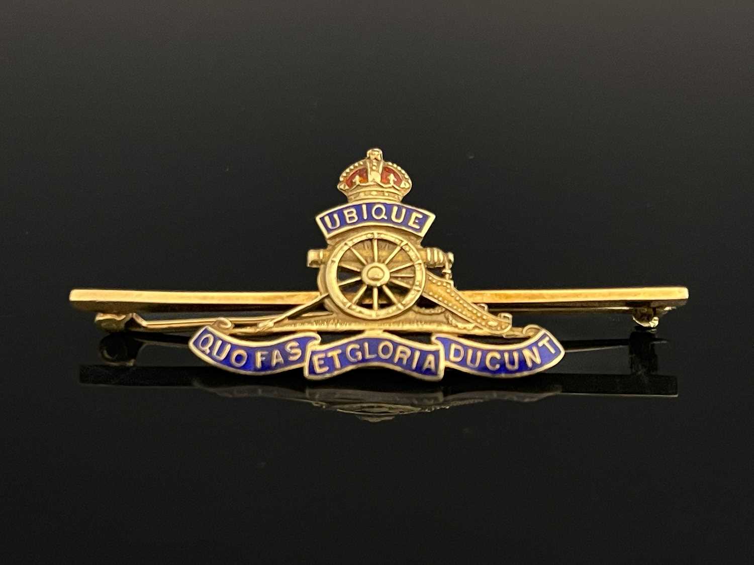 A 15 carat gold and enamelled Royal Artillery bar brooch, cast and pierced emblem with blue enamel