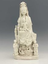 A Chinese blanc de Chine figure of Guanyin, modelled with child on its knee, two further figues