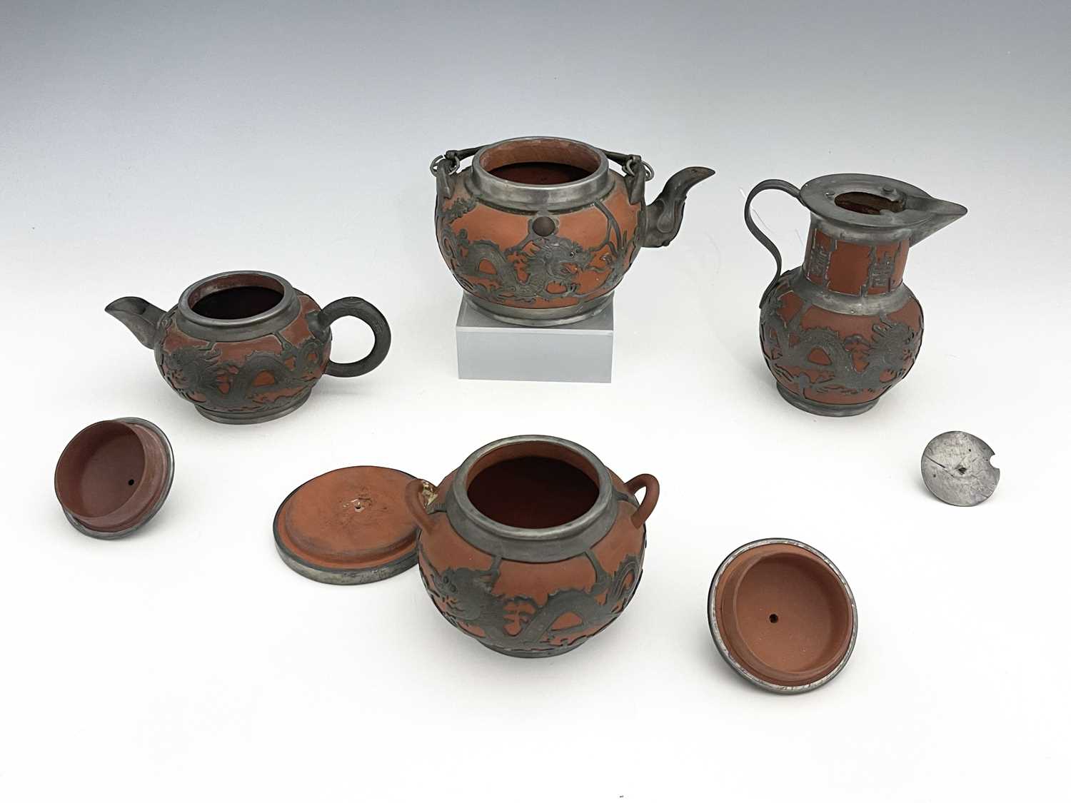 A Chinese Yixing four piece tea set, pewter overlaid redware, chased dragon design below Chinese