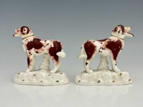 A pair of Staffordshire porcelain figures of dogs, modelled standing on gilt tufted bases, mouths