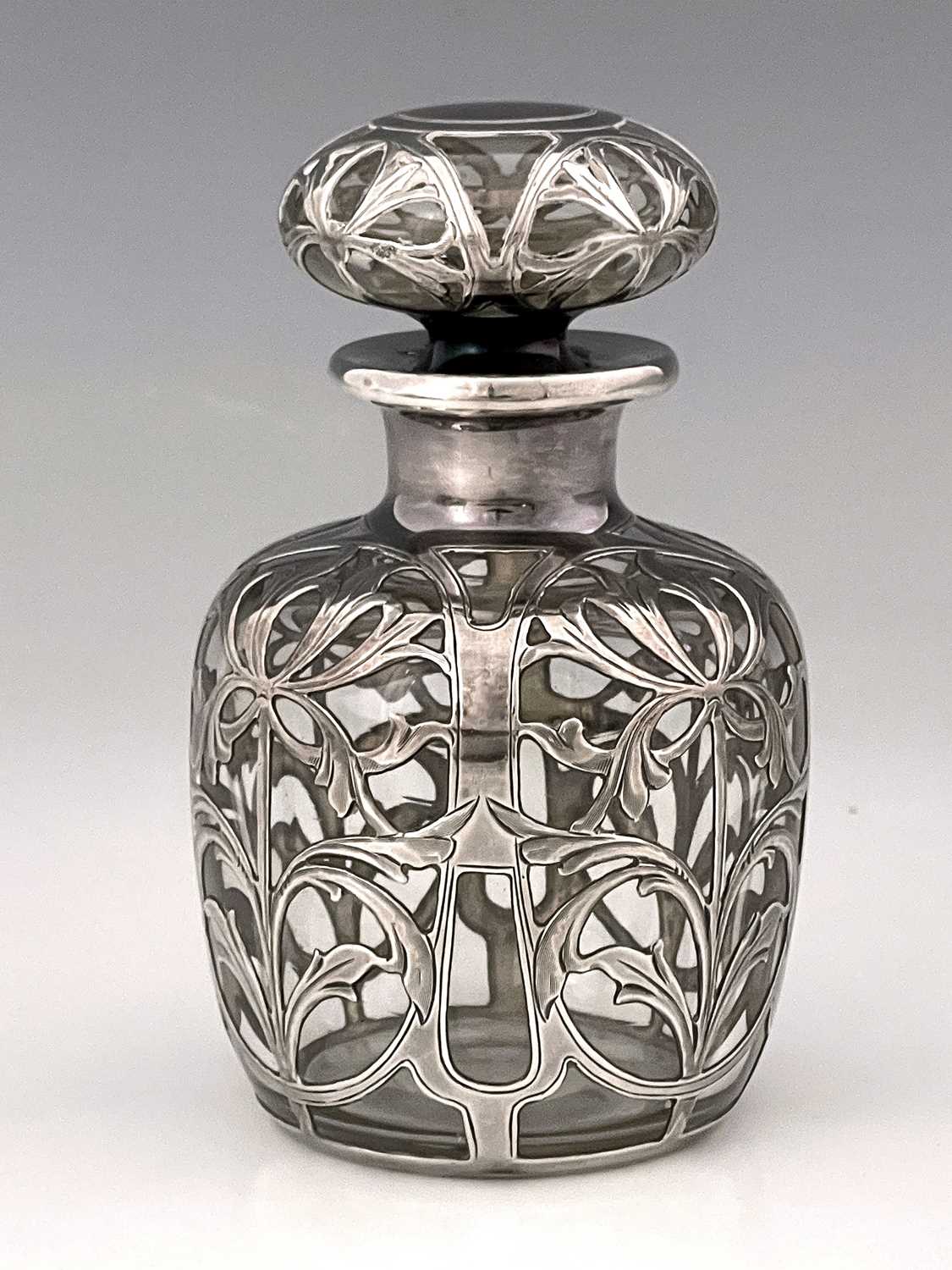 An American Art Nouveau silver overlay glass perfume bottle and stopper, ovoid form, chased with