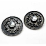 A pair of Arts and Crafts silver and mother of pearl buttons, circular form applied with coiled C