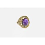 A Modernist 9 carat gold and amethyst cabochon ring, the oval stone in a bark textured nest of