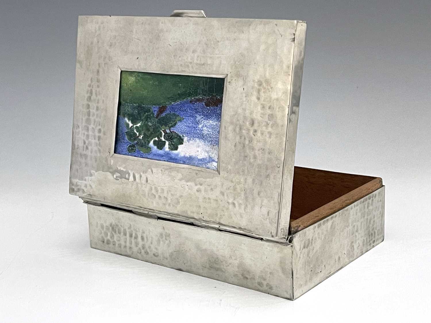 An Arts and Crafts pewter and enamelled box, circa 1920, planished cuboid form, the lid inset with a