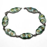 An Arts and Crafts silver and enamelled bracelet, seven links, each with stylised leaves within ogee