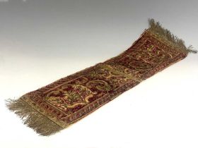 A 17th century gilt embroidered velvet religious hanging, red ground with foliate scroll and