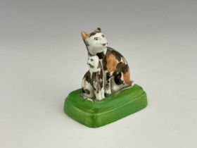 A Staffordshire porcelain cat and kitten figure group, modelled as tortoiseshell cats on a green