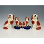 Two pairs of Staffordshire dog figures, one pair modelled as spaniels holding floral baskets, the