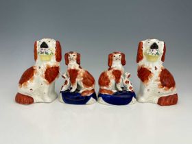 Two pairs of Staffordshire dog figures, one pair modelled as spaniels holding floral baskets, the