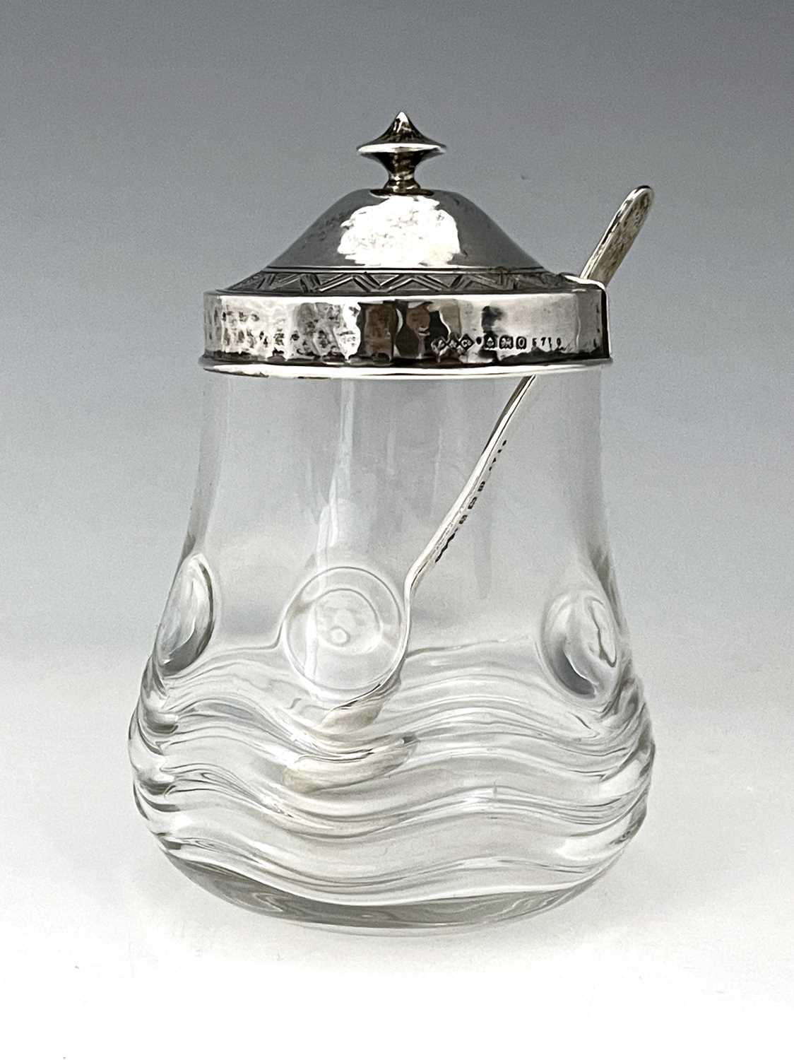 Bernard Cuzner for Liberty and Co., an Arts and Crafts silver lidded glass preserve jar and spoon,