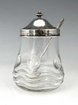 Bernard Cuzner for Liberty and Co., an Arts and Crafts silver lidded glass preserve jar and spoon,