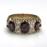 A 9 carat gold and garnet ring, two rows of three white stones between three facet cut red stones on
