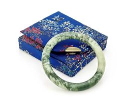 A Chinese green jade bangle bracelet, moss veined, 8cm diameter