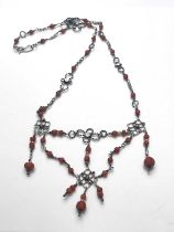 An Arts and Crafts silver and coral necklace, formed of knotted ropetwist quatrefoil and ring