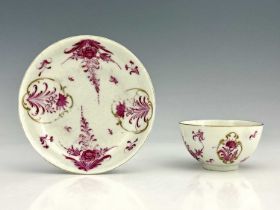 A Worcester tea bowl and sacucer, circa 1765, painted in the Meissen style with puce floral