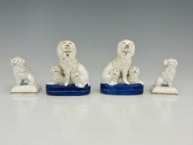 Two pairs of Staffordshire dogs, one with family groups of poodles and puppies on blue bases, the