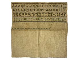 An 18th century sampler, embroidered in green with alphabet and numbers in four rows, 17cm square,