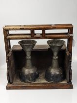 An 18th or 19th century Chinese or Tibetan wooden carrying case with two pewter Yak butter temple