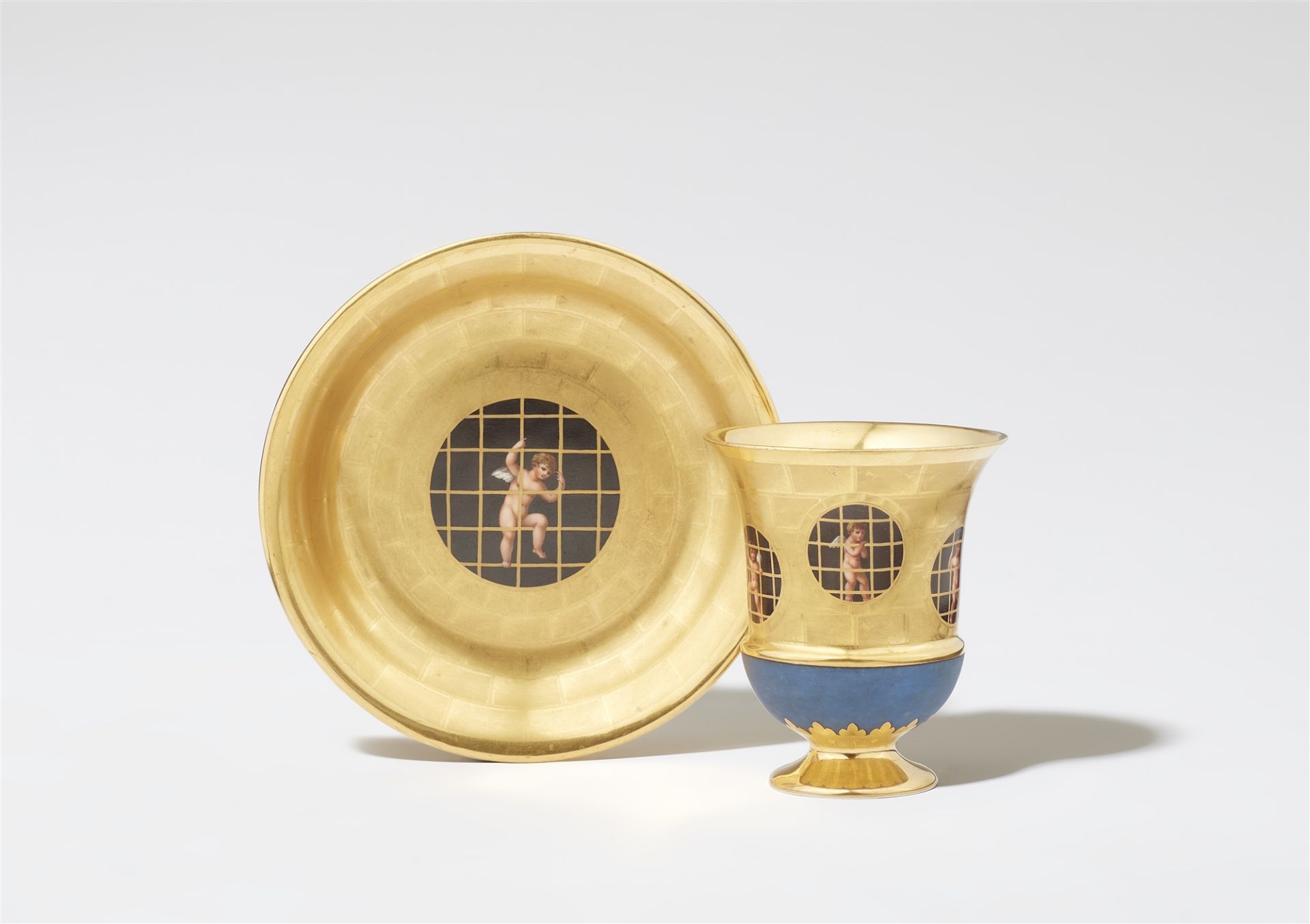 A Berlin KPM porcelain cup and saucer with putti behind bars