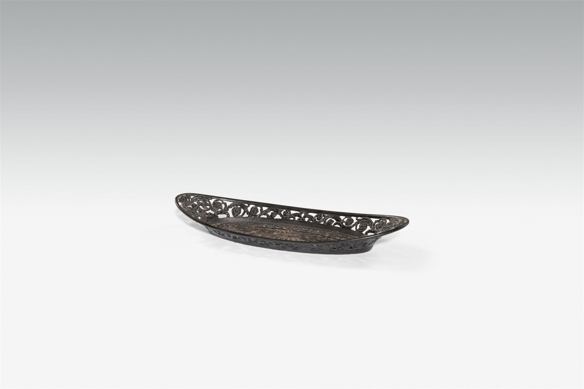 A cast iron wick trimmer plate with oak leaf relief