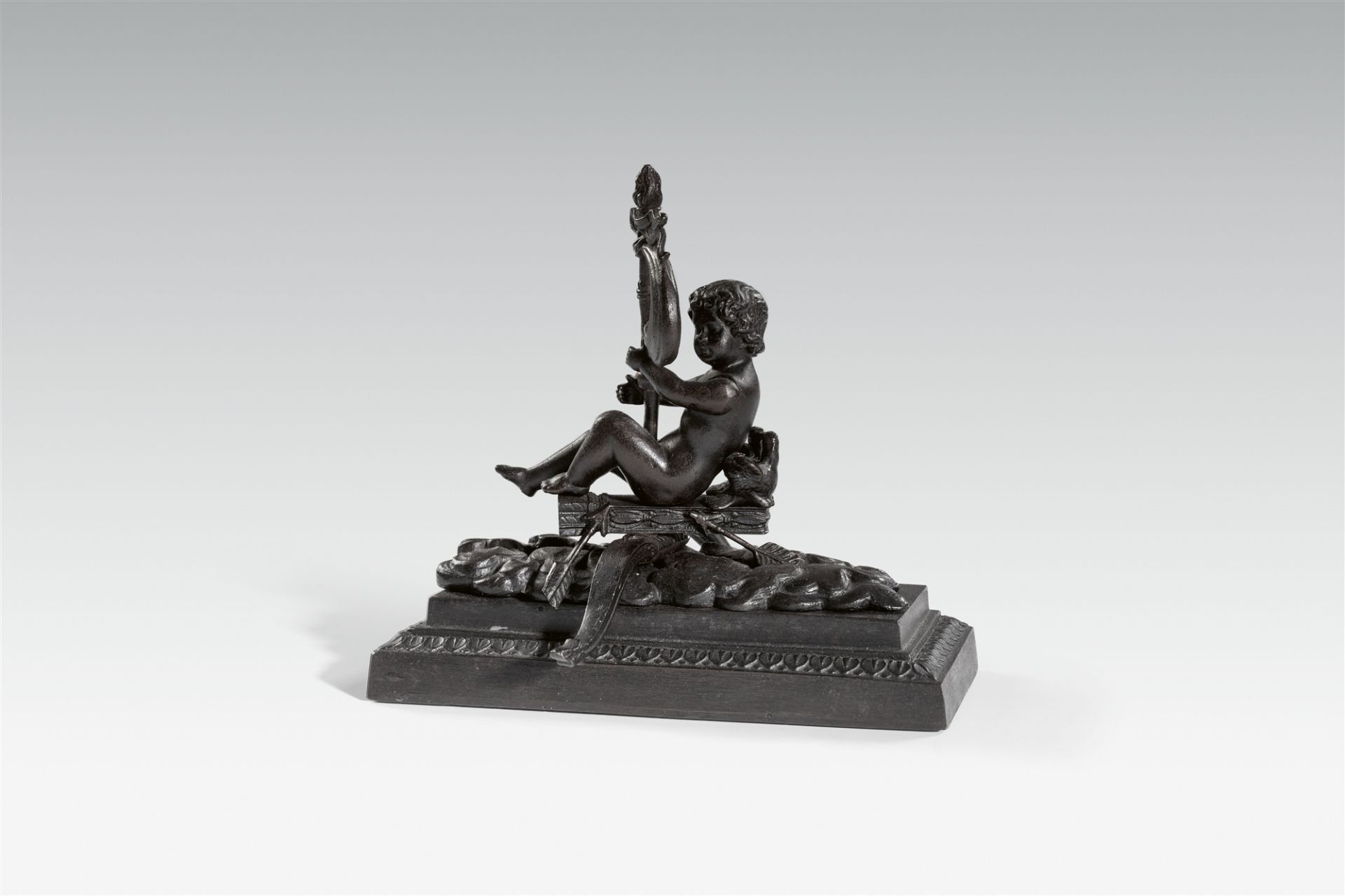 A cast iron paperweight with a figure of Cupid sailing