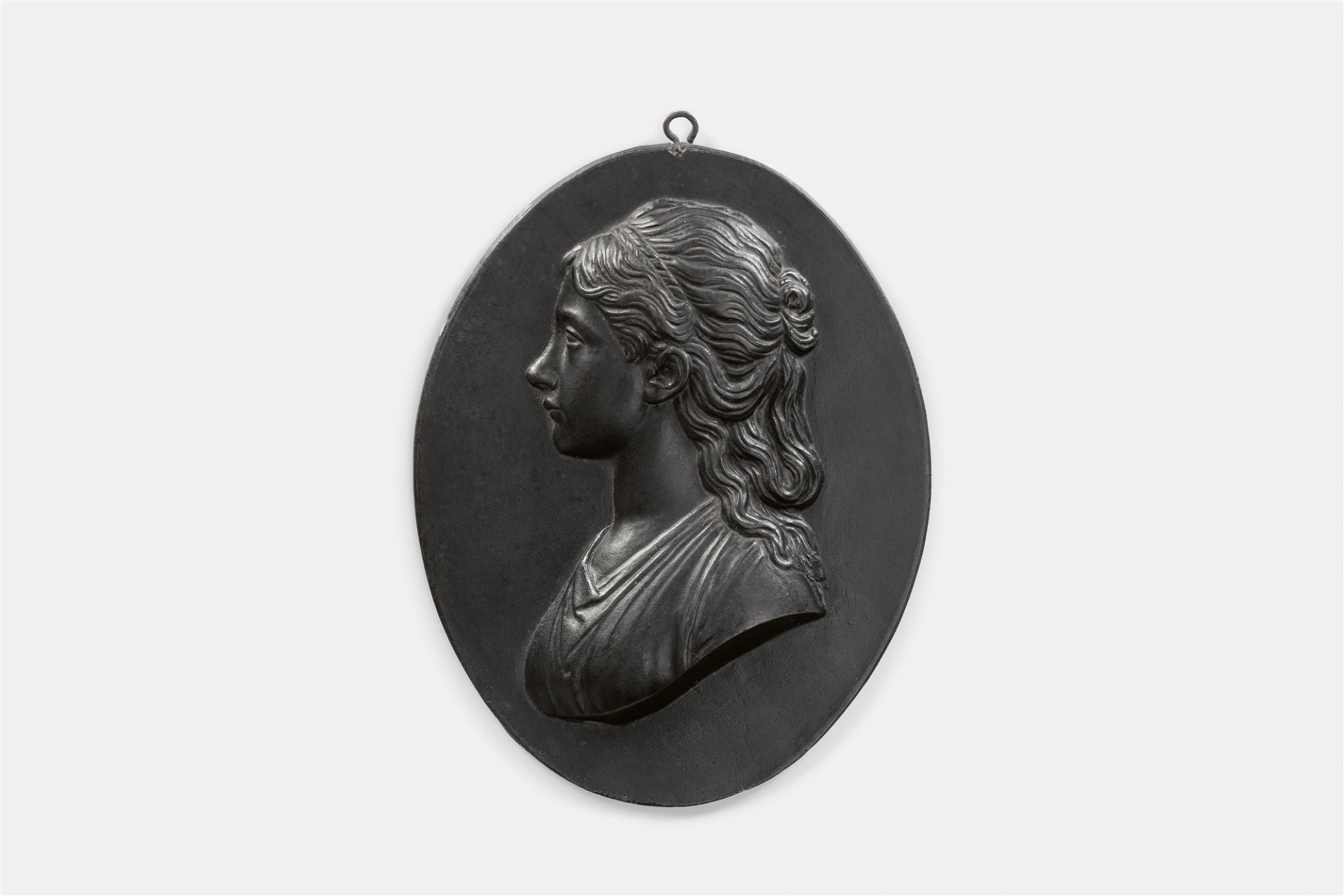 An oval cast iron plaque with a portrait of a lady