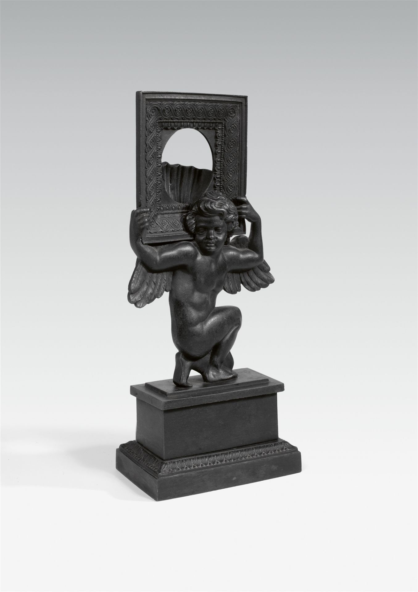 A cast iron portremontre with a putto and frame
