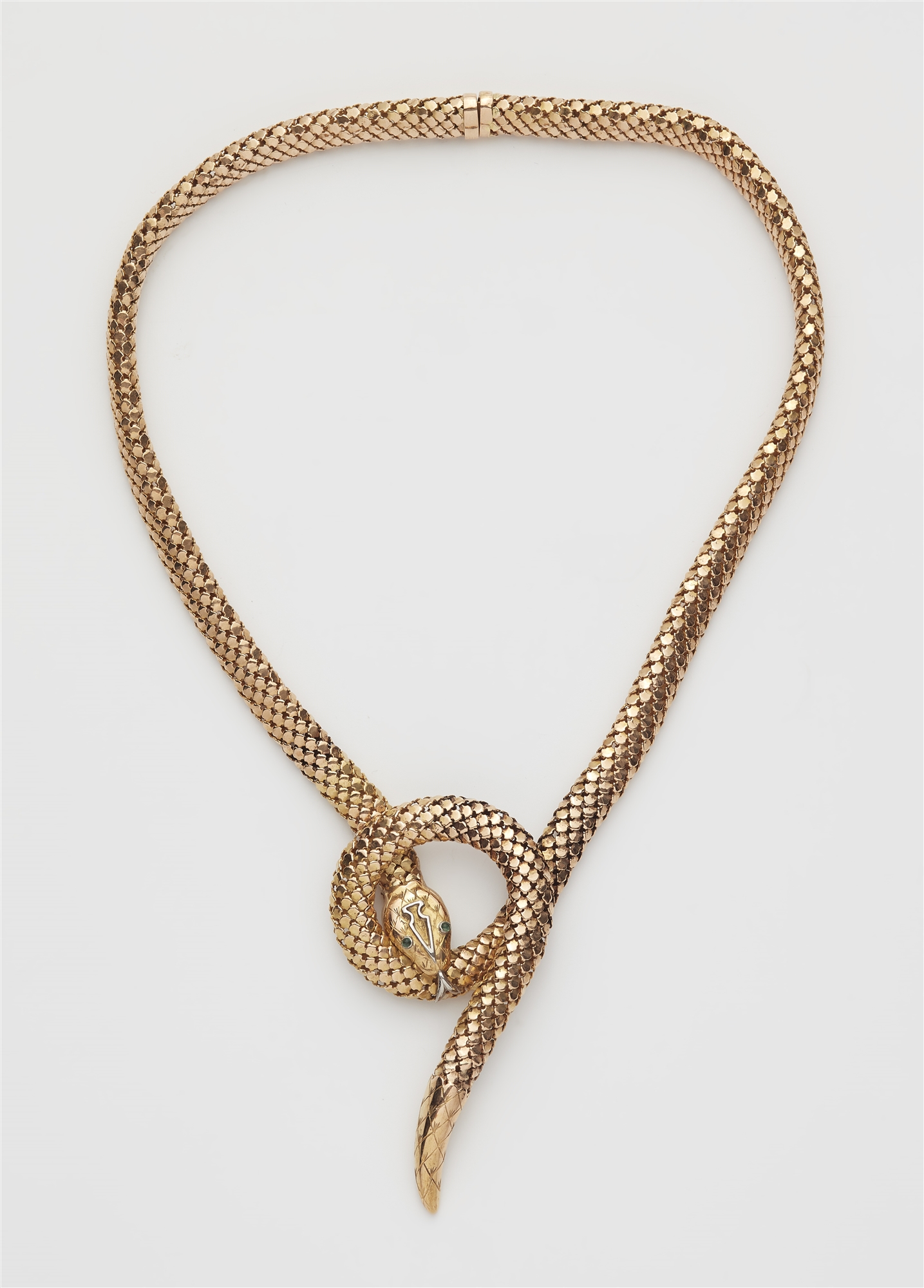 A flexible 18k red gold tubogaz snake necklace with emerald eyes.