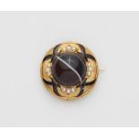 A Victorian 14k gold black enamel and pearl memory brooch with a large banded onyx cabochon.