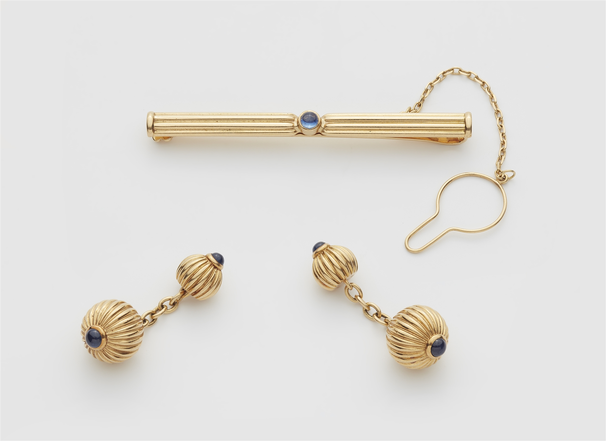 A pair of French godrooned 18k gold and sapphire tie clip and pair of double sided cufflinks.