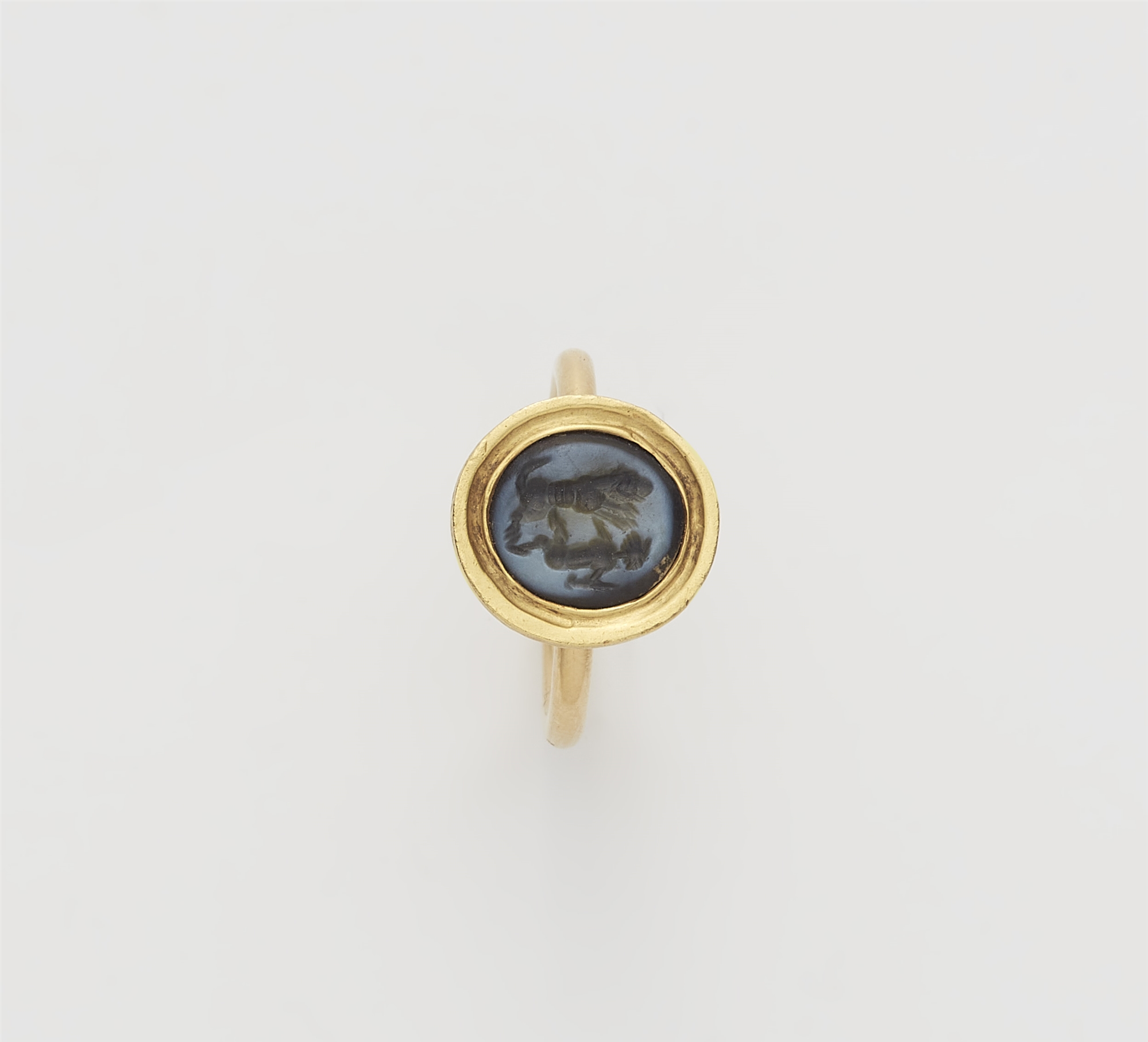 An 18k gold ring with an ancient Sassanian nicolo intaglio depicting a lion fighting with a hoofed a