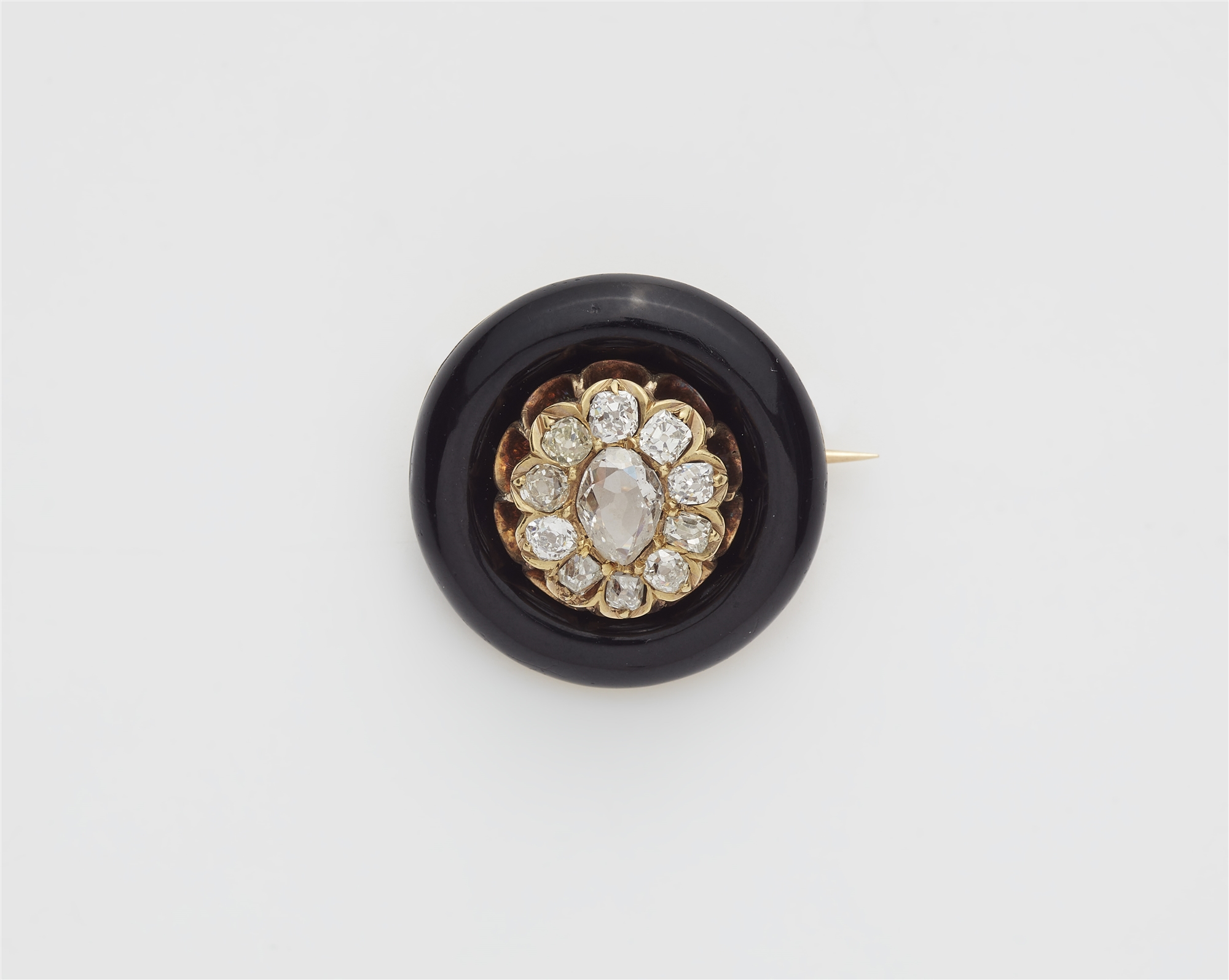 A 14k gold black enamel and diamond circular brooch.